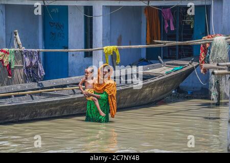 Bogura, Bangladesh. 15 juillet 2020. Une femme avec son enfant se tient devant leur maison inondée.au moins 1.5 millions de personnes ont été touchées, avec des maisons et des routes dans les villages inondés. Selon les responsables du Centre de prévision et d'alerte des inondations (FFWC), la situation des inondations dans 15 districts du nord et du centre est due à l'augmentation des niveaux d'eau des principaux fleuves, y compris le Brahmaputra, Jamuna, Padma, Teesta et Dharla. Crédit : Zabed Hasnain Chowdhury/SOPA Images/ZUMA Wire/Alay Live News Banque D'Images