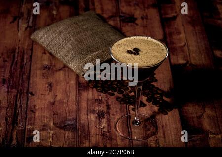 Dose d'espresso martini à grand angle avec grains de café sur une surface en bois Banque D'Images