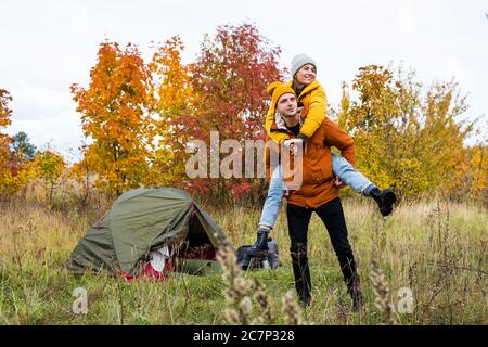 voyage, trekking et randonnée concept - portrait de couples randonneurs ayant l'amusement près de la tente verte dans la belle forêt d'automne Banque D'Images