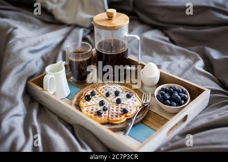 petit déjeuner - gros plan sur un plateau en bois avec de la nourriture savoureuse sur le lit Banque D'Images