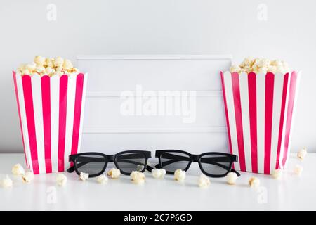 cinema concept - boîtes à rayures rouges avec pop-corn, lunettes 3d, boîte lumineuse vierge avec espace de copie Banque D'Images