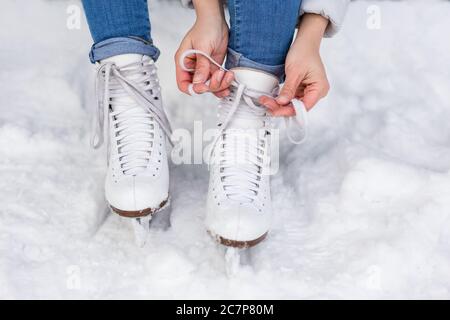 gros plan des mains de femmes nouant des patins blancs sur la zone de glace de la patinoire Banque D'Images