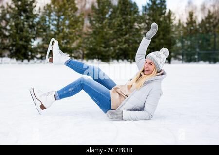 drôle fille tombant pendant que patinage sur glace à la patinoire d'hiver Banque D'Images