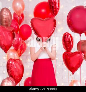 concept de la saint-valentin - femme mince couvrant son visage avec ballon en forme de coeur Banque D'Images