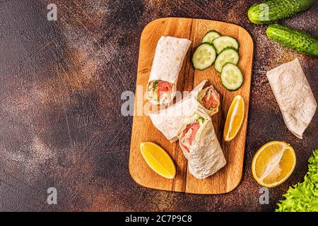 Sandwich emballé avec saumon, laitue, concombre et fromage à la crème, vue de dessus. Banque D'Images