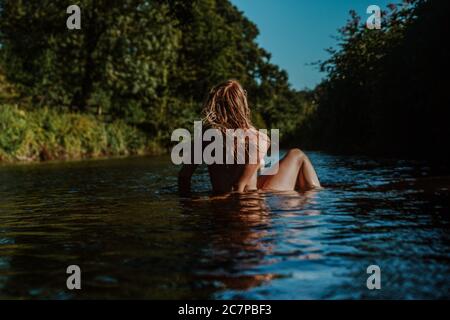 Belle femme skinny trempant et nageant sauvage dans la rivière Banque D'Images