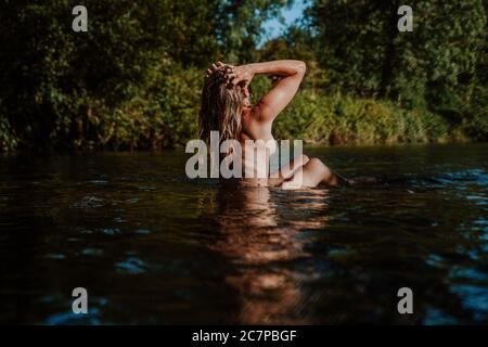 Belle femme skinny trempant et nageant sauvage dans la rivière Banque D'Images