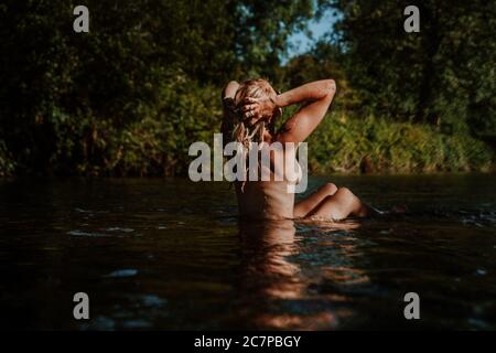 Belle femme skinny trempant et nageant sauvage dans la rivière Banque D'Images