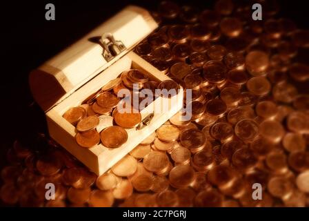 Gros plan horizontal d'une petite poitrine en bois pleine de pièces de monnaie comme le Trésor pirate classique, reposant sur une montagne de centimes d'euro. Banque D'Images