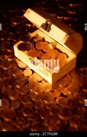 Gros plan vertical d'une petite poitrine en bois pleine de pièces de monnaie comme le Trésor pirate classique, reposant sur une montagne de centimes d'euro. Banque D'Images