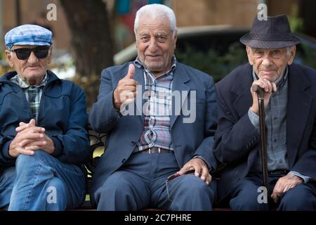 Trois retraités siègent et parlent sur un banc public dans le parc Cascades, dans le quartier Monument d'Erevan, en Arménie. Banque D'Images