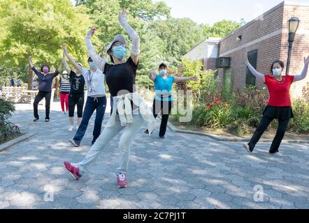 En portant des masques et en observant la distance, un groupe de femmes américaines chinoises pratiquent la danse chinoise moderne. À Flushing, Queens, New York Banque D'Images