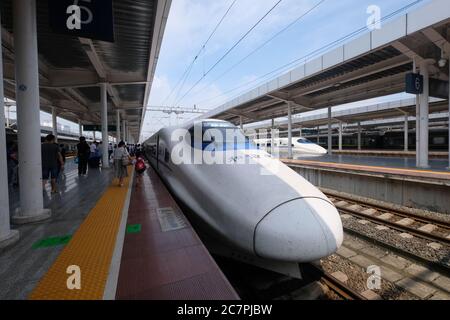 Grand angle de China Railway train à grande vitesse (CRH ) sur chemin de fer sous le soleil. Passagers marchant sur une plate-forme. Vue en perspective Banque D'Images