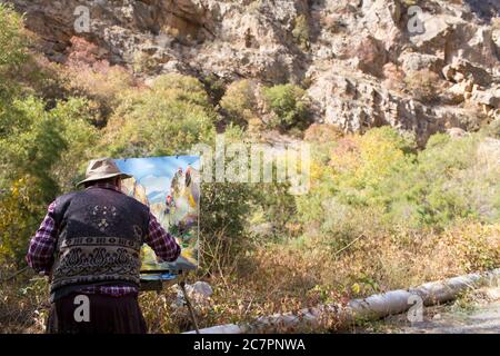 Un artiste peint les spectaculaires vallées et collines aux couleurs automnales autour du complexe du monastère de Noravank dans l'ouest de l'Arménie. Banque D'Images