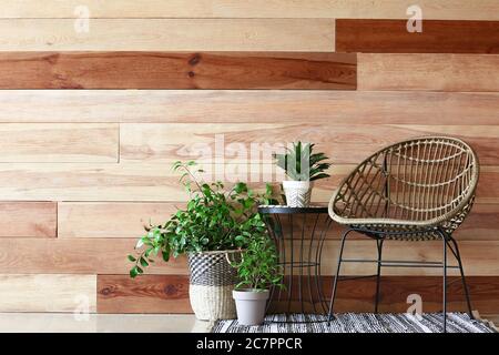 Plantes de maison vertes avec fauteuil près du mur en bois Banque D'Images