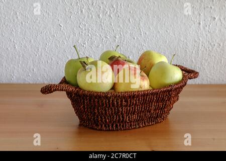 Pommes dans un petit panier sur une table en bois Banque D'Images