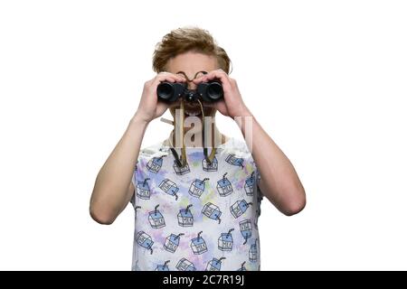 Un adolescent souriant et joyeux regarde à travers des jumelles. Banque D'Images