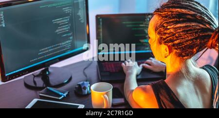 Une jeune femme moderne programmeur écrit le code de programme sur un ordinateur portable à la maison. Travail à distance dans le secteur INFORMATIQUE. Le concept de développement logiciel. Banque D'Images