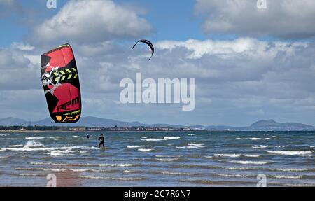 Longniddry, East Lothian, Écosse, Royaume-Uni. 19 juillet 2020. Photo : Natalie, surfeuse de cerf-volant, a attrapé 10 minutes de vent de la direction ouest avant que les conditions ne deviennent moins favorables et les rafales où moins approprié pour l'ascenseur sur le Firth of Forth, avec la ville d'Édimbourg et Arthurs Seat en arrière-plan. Température de 16 degrés vif et nuageux avant midi quand le nuage plus épais a été déplacé. Banque D'Images