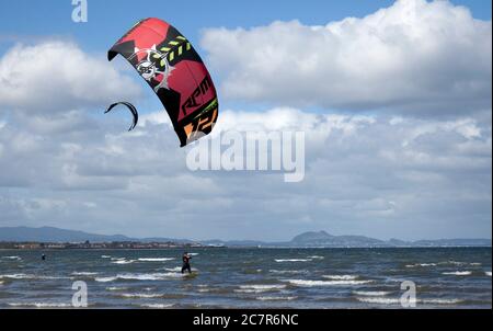 Longniddry, East Lothian, Écosse, Royaume-Uni. 19 juillet 2020. Photo : Natalie, surfeuse de cerf-volant, a attrapé 10 minutes de vent de la direction ouest avant que les conditions ne deviennent moins favorables et les rafales où moins approprié pour l'ascenseur sur le Firth of Forth, avec la ville d'Édimbourg et Arthurs Seat en arrière-plan. Température de 16 degrés vif et nuageux avant midi quand le nuage plus épais a été déplacé. Banque D'Images