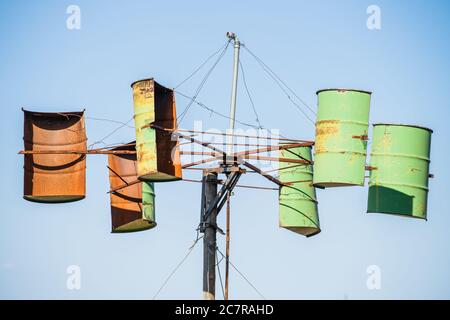 Moulin à vent artisanal fabriqué à partir de vieilles moitiés de barils rouillés sur un fond ciel bleu clair Banque D'Images