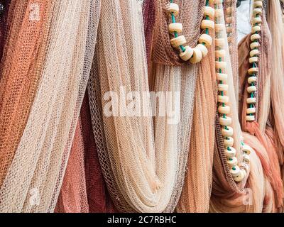 Gros plan de filets de pêche multicolores suspendus et de perles blanches sur une corde verte Banque D'Images