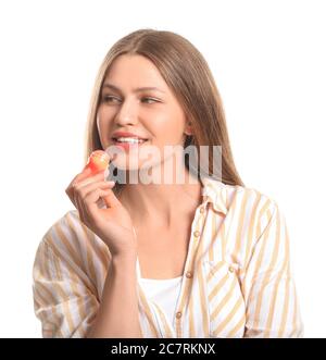 Belle jeune femme avec baume à lèvres sur fond blanc Banque D'Images