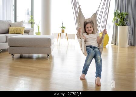 Adorables petites filles assises sur le hamac dans la maison Banque D'Images