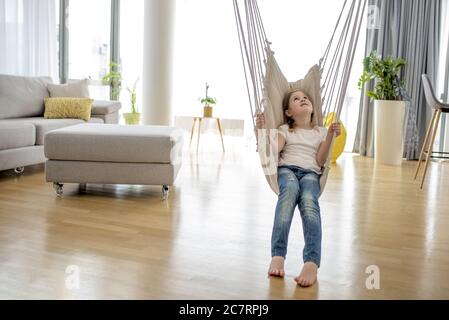 Adorables petites filles assises sur le hamac dans la maison Banque D'Images