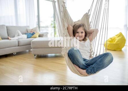 Adorable petite fille assise sur le hamac dans la maison Banque D'Images