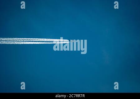 L'avion et les pistes de condensation sur le fond bleu clair du ciel - parfait pour le papier peint Banque D'Images