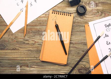 Carnet avec stylos à plume, encre et brosses sur table Banque D'Images