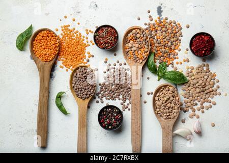 Cuillères avec lentilles et épices sur fond blanc Banque D'Images