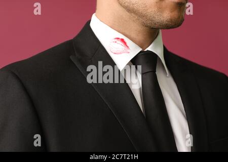 Jeune homme d'affaires avec imprimé lèvres sur col chemise sur fond de couleur, gros plan Banque D'Images