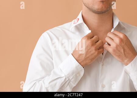 Jeune homme d'affaires avec imprimé lèvres sur col chemise sur fond de couleur, gros plan Banque D'Images