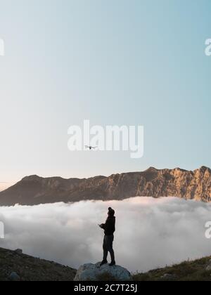 Homme à l'extérieur avec télécommande volant un drone dans les montagnes avec le ciel sur horison Banque D'Images