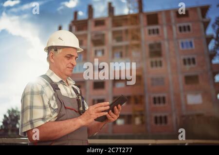 Directeur de la construction contrôlant le chantier avec une tablette pc au coucher du soleil Banque D'Images