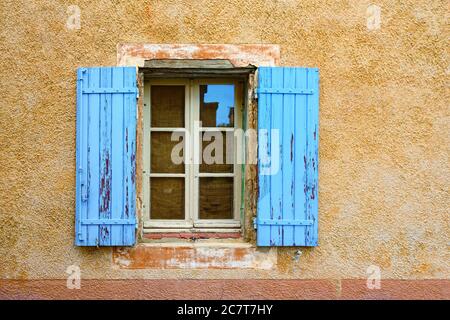 Fenêtre ouverte avec volets en bois couleur lavande sur un mur en plâtré couleur ocre. Village Roussillon, Provence, France Banque D'Images