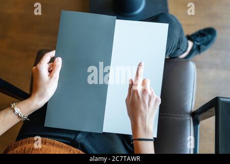 femme tient et pointe sur une page vide comme modèle de texture, carte, menu ou brochure . Photo de haute qualité Banque D'Images