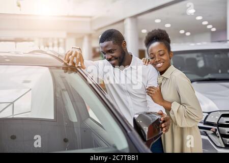 portrait de beau couple marié africain est venu dans la concession pour acheter leur première voiture familiale. les clients heureux font l'achat, choisir Banque D'Images