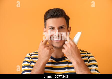 Jeune homme appliquant de la crème solaire sur fond de couleur Banque D'Images