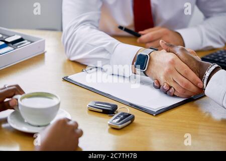 un responsable professionnel confiant remet les clés de la nouvelle voiture au client et lui remet les clés, le client achète à la concession Banque D'Images