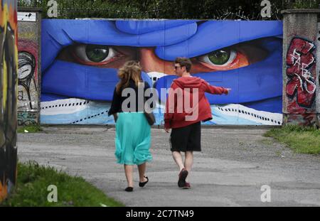 Les gens marchent devant l'artiste basé à Dublin Asbestos dernière dans sa série de portraits masque, la fresque dans le centre-ville de Dublin est intitulé 'Protégez-nous' et souligne la nécessité de porter des masques de protection dans l'effort de contrôler la propagation de Covid-19. Banque D'Images