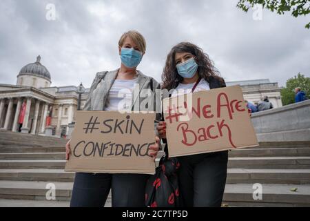 Londres, Royaume-Uni. 19 juillet 2020. Coronavirus : Industrie des services de beauté. Deux travailleurs masqués de l'industrie du service professionnel de beauté tiennent des panneaux de promotion de la sensibilisation de beauté à Trafalgar Square. Le 17 juillet, le Premier ministre Boris Johnson a annoncé que tous les services de beauté en Angleterre peuvent reprendre à partir du 1er août. Cela inclut des services de contact étroit, tels que le filetage des sourcils et les soins du visage, qui ont été soumis à de lourdes restrictions tout au long du verrouillage. Crédit : Guy Corbishley/Alamy Live News Banque D'Images