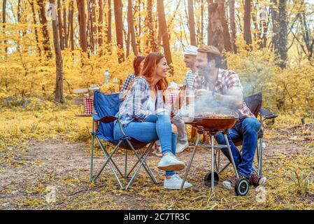Groupe de jeunes amis ayant un pique-nique barbecue dans un garez-vous par temps ensoleillé Banque D'Images