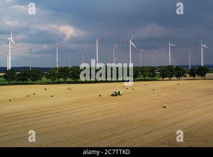 Petersdorf, Allemagne. 19 juillet 2020. Des nuages de tempête sombres se déplacent sur un parc éolien tandis qu'au premier plan un agriculteur presse la paille en rouleaux (vue aérienne avec un drone). Credit: Patrick Pleul/dpa-Zentralbild/dpa/Alay Live News Banque D'Images