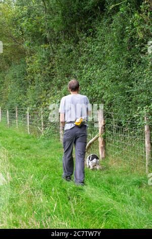 Homme qui va faire une promenade le dimanche en été avec son chien, un cafpoo, à Wealden, dans l'est du Sussex Banque D'Images