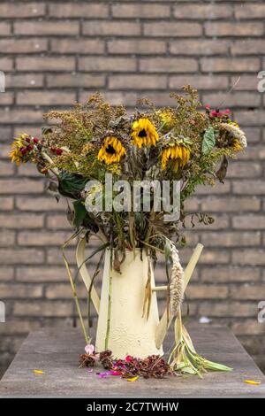 À la légère baisse par rapport à un vase de mourir, d'arrangement de fleur grand une fois mourir maintenant lumineux soleil fleurs dans un vase sur une très grande table à manger en marbre Banque D'Images