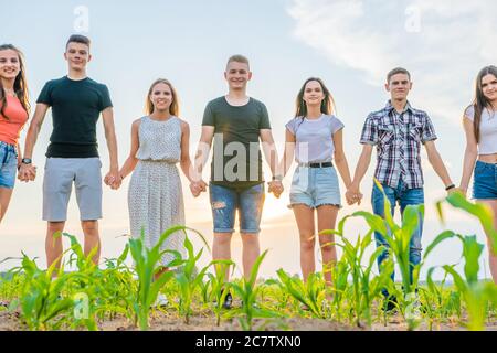 Concept de cohésion. Un groupe d'amis se tient les mains au coucher du soleil. Banque D'Images