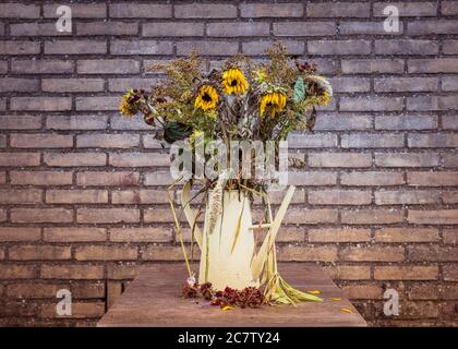 À la légère baisse par rapport à un vase de mourir, d'arrangement de fleur grand une fois mourir maintenant lumineux soleil fleurs dans un vase sur une très grande table à manger en marbre Banque D'Images